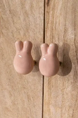 Two small blush rabbit-shaped hooks mounted on natural timber.