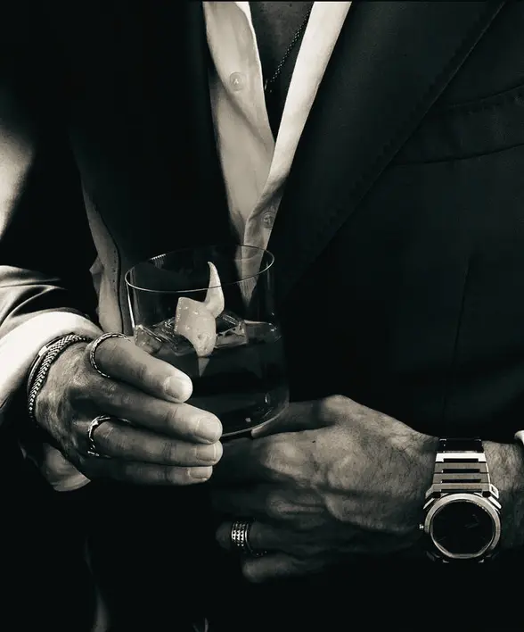Monochrome reference of a tailored suit, watch and drink.